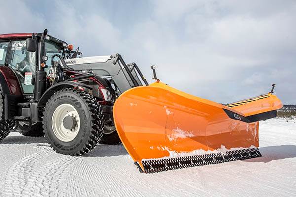 Traktor och plog på väg med snö