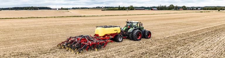 Såmaskin och grön traktor på ett fält med vy mot horisonten. Väderstad Seed Hawk och Fendt.